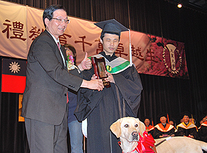 「資訊管理研究所」畢業生蔡國寶(右)，在導盲犬「Aspen」導引下，
雙雙接受教育部長吳清基(左)的頒獎